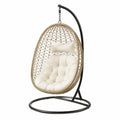 Chaise suspendue en rotin avec coussin beige et support en métal